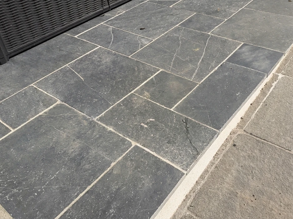Terrasse extérieure en dalles de pierre naturelle type ardoise ou schiste bleu-gris, posées en appareillage décalé