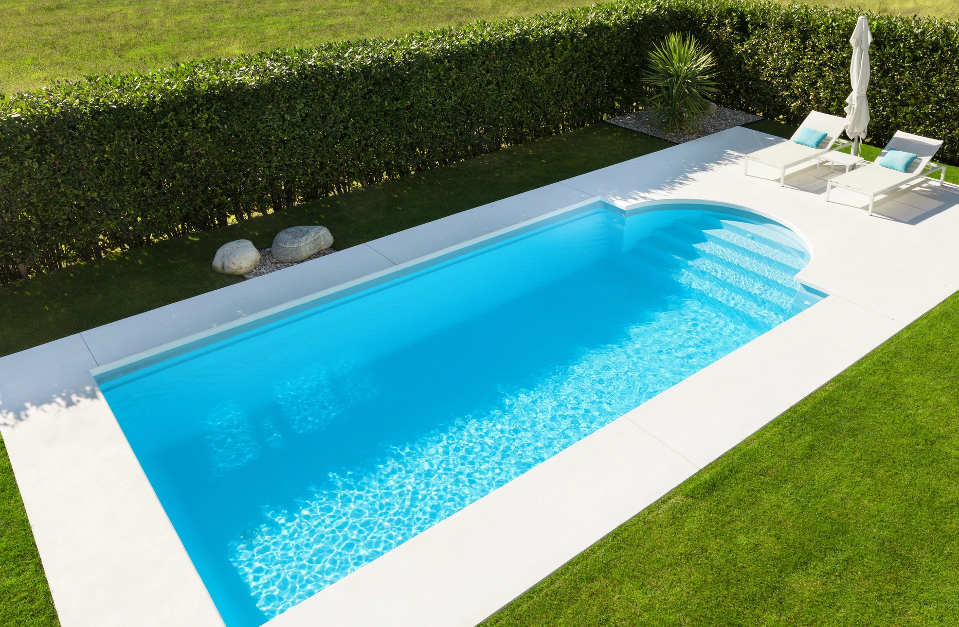 Vue aérienne d'une piscine rectangulaire avec eau turquoise cristalline et plage en bois exotique