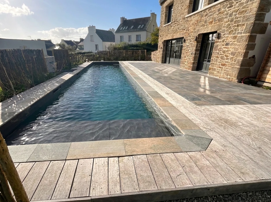 Terrasse extérieure en dalles de pierre naturelle type ardoise ou schiste bleu-gris, posées en appareillage décalé