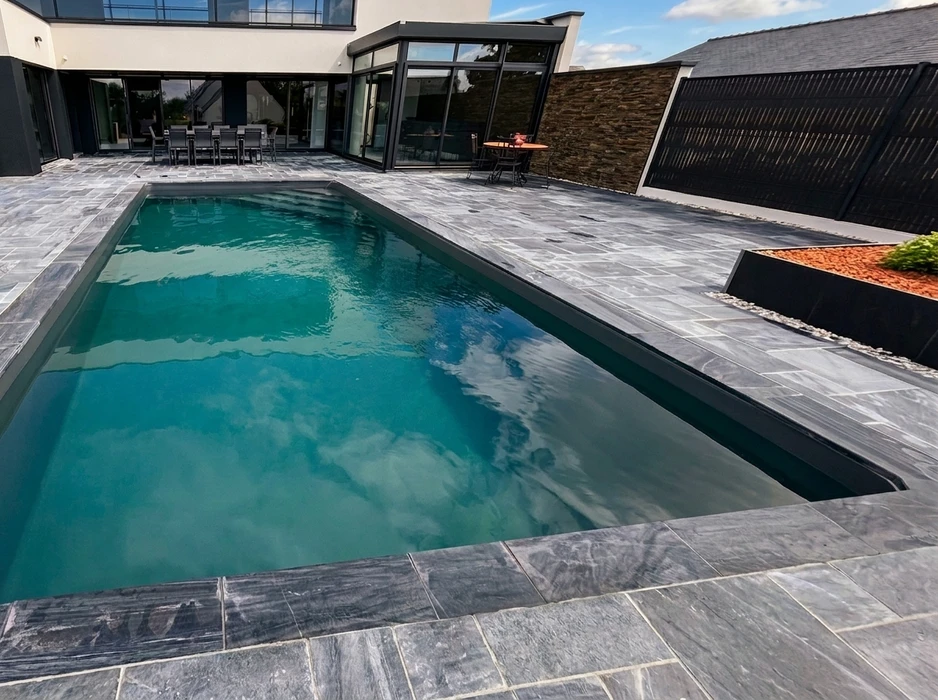 Terrasse extérieure en dalles de pierre naturelle type ardoise ou schiste bleu-gris, posées en appareillage décalé