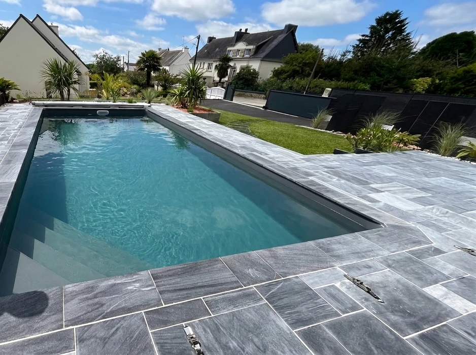 Terrasse extérieure en dalles de pierre naturelle type ardoise ou schiste bleu-gris, posées en appareillage décalé