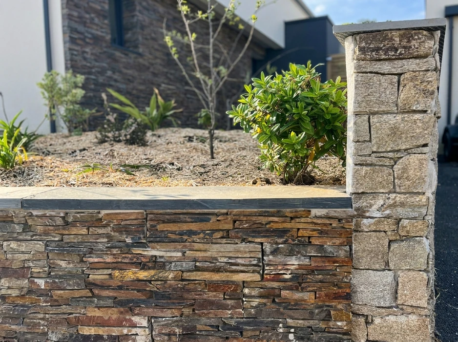 Terrasse extérieure en dalles de pierre naturelle type ardoise ou schiste bleu-gris, posées en appareillage décalé
